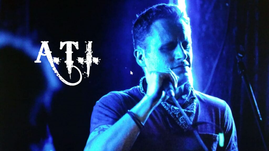 Patrik Terhorst der Band A.T.I. mit einem Mikrofon in der Hand. Das Bild hat einen Blaufilter.